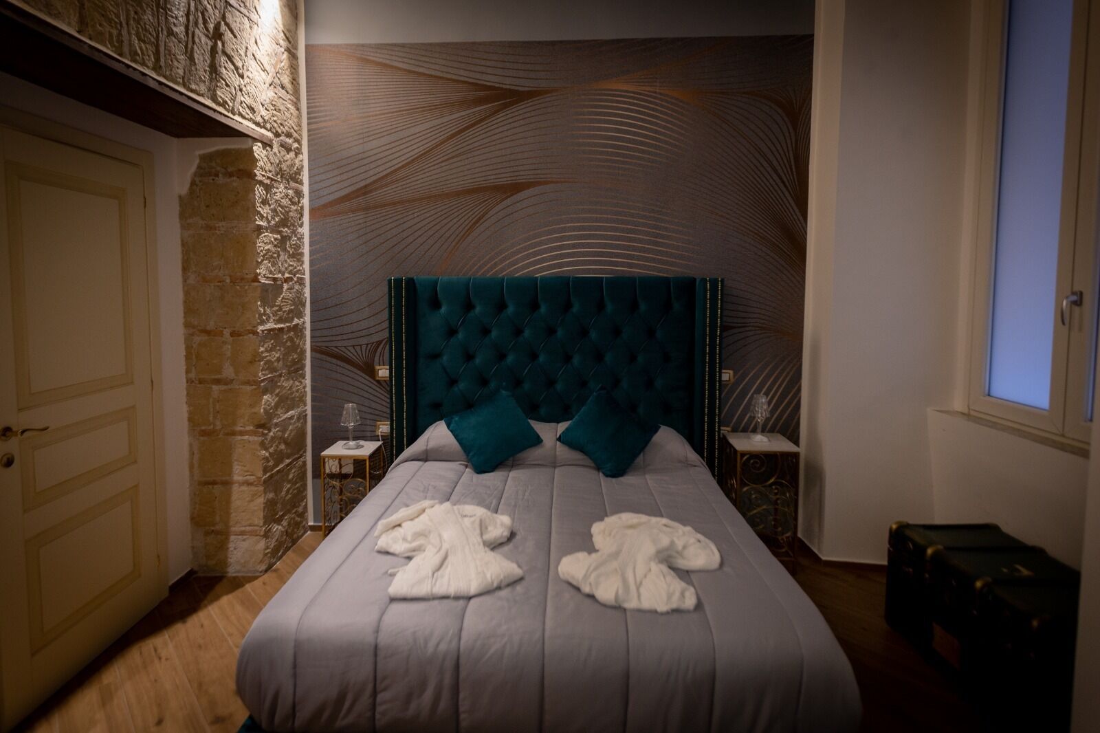 Ein Schlafzimmer mit einem großen Bett, einer Steinwand und einem Fenster.