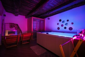 A room with a wooden ceiling, a bathtub, a bench, and a wall with circular decorations. - Petramare Charming House: an oasis of wellness and relaxation with a spa in the heart of Salerno (SALERNO)