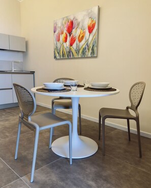 Un comedor con una mesa redonda, dos sillas y un cuadro de tulipanes en la pared.