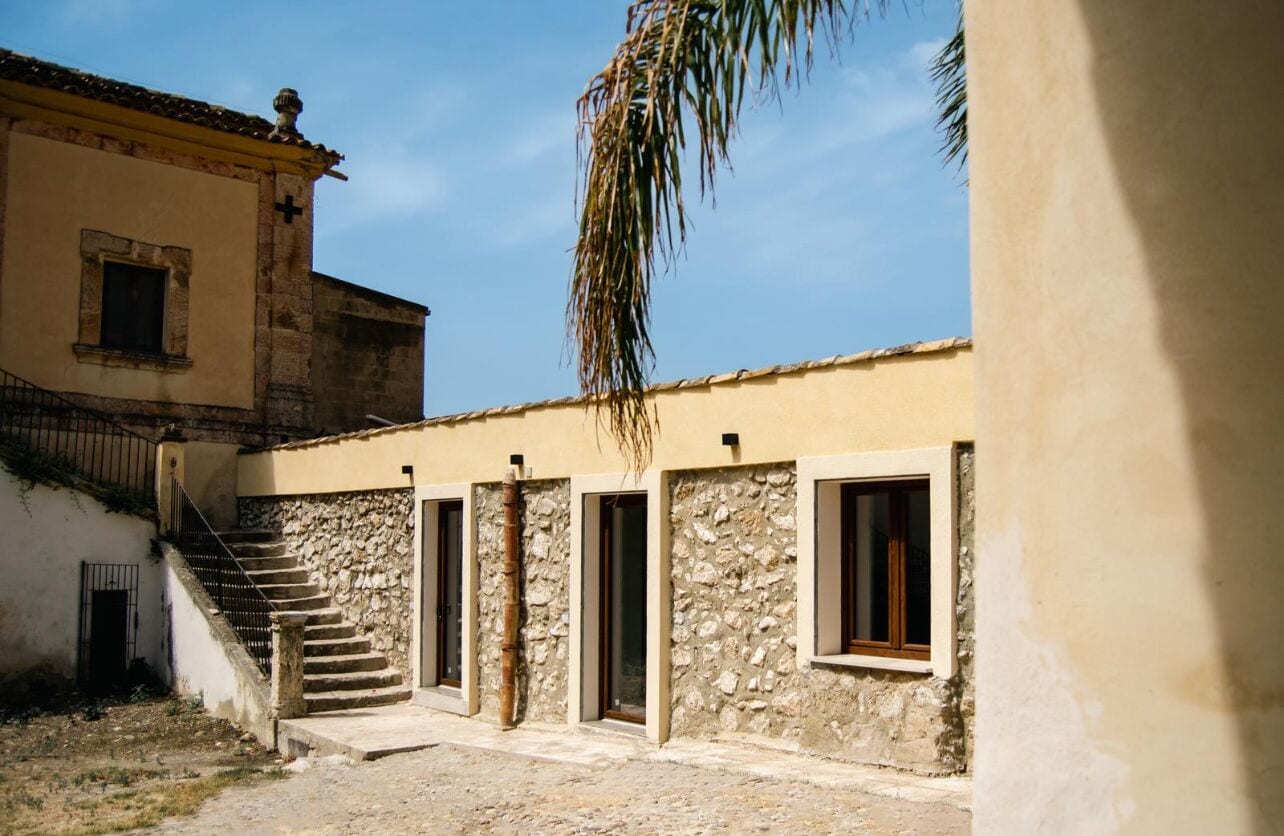 A courtyard with a stone staircase leading to a building with multiple doors and windows.
