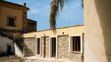 A courtyard with a stone staircase leading to a building with multiple doors and windows.