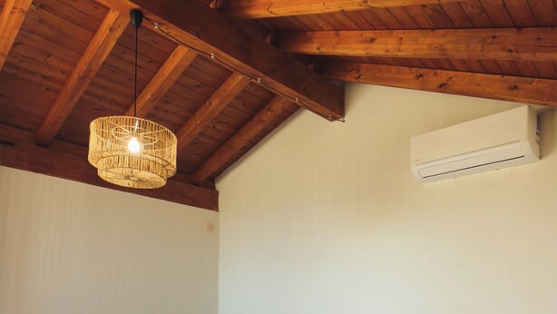 A bedroom with a bed, a small stool, a hanging light fixture, and an air conditioning unit. - Baglio Capo  (siculiana)