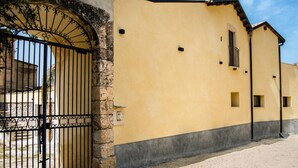 A yellow building with a gated entrance, a small window, and a door. - Baglio Capo  (siculiana)