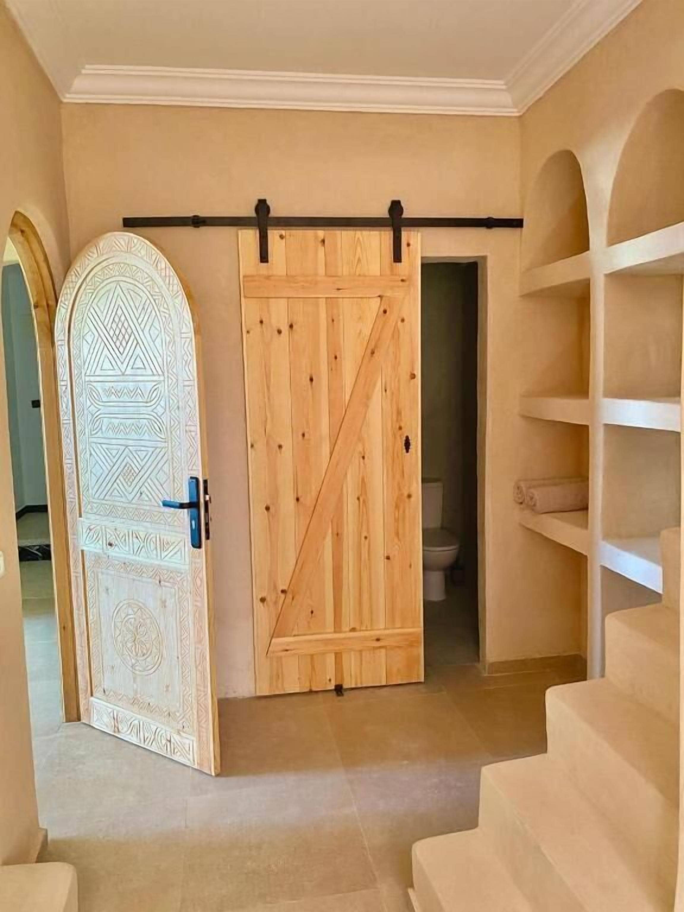 Una habitación con puerta corredera de madera, puerta estampada y una escalera.