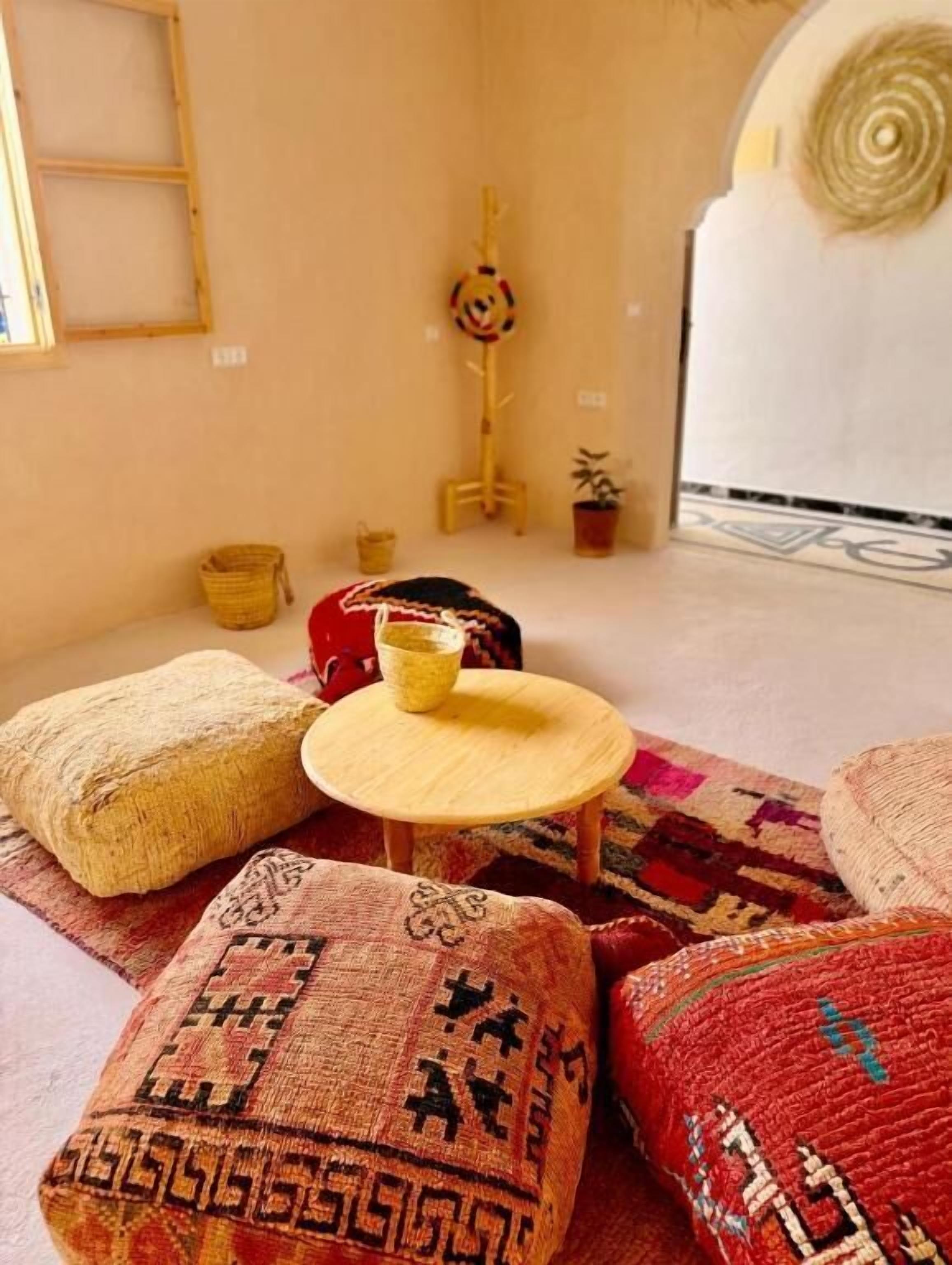 Una habitación acogedora con una mesa redonda de madera, un tapete estampado y una pequeña planta en maceta.