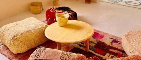 Una habitación acogedora con una mesa redonda de madera, un tapete estampado y una pequeña planta en maceta.