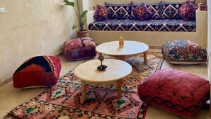 A cozy living room with a sofa, two round tables, and colorful cushions. - Sines Surfmaroc (Aourir)