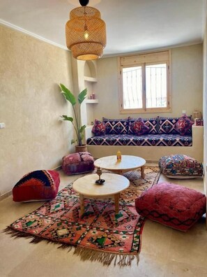 A cozy living room with a sofa, two round tables, and colorful cushions. - Sines Surfmaroc (Aourir)