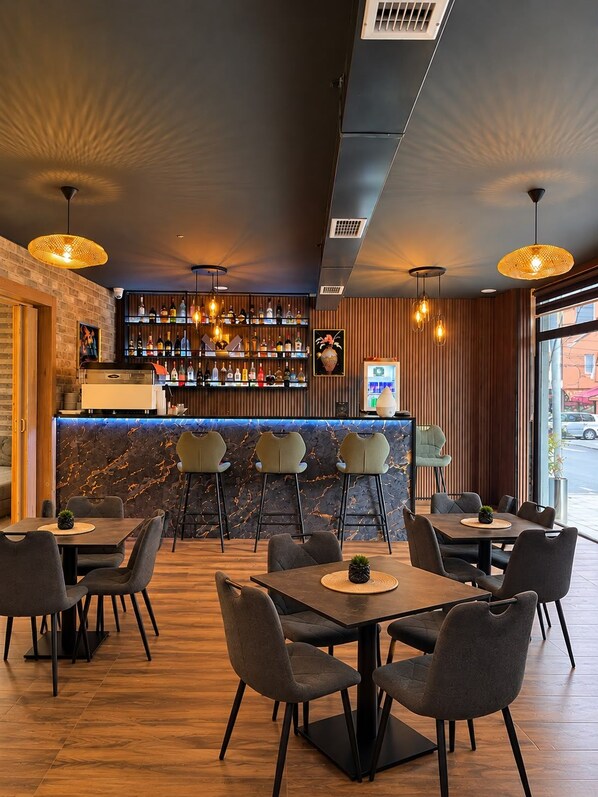 A modern bar area with a marble countertop, multiple bar stools, and a selection of bottles.