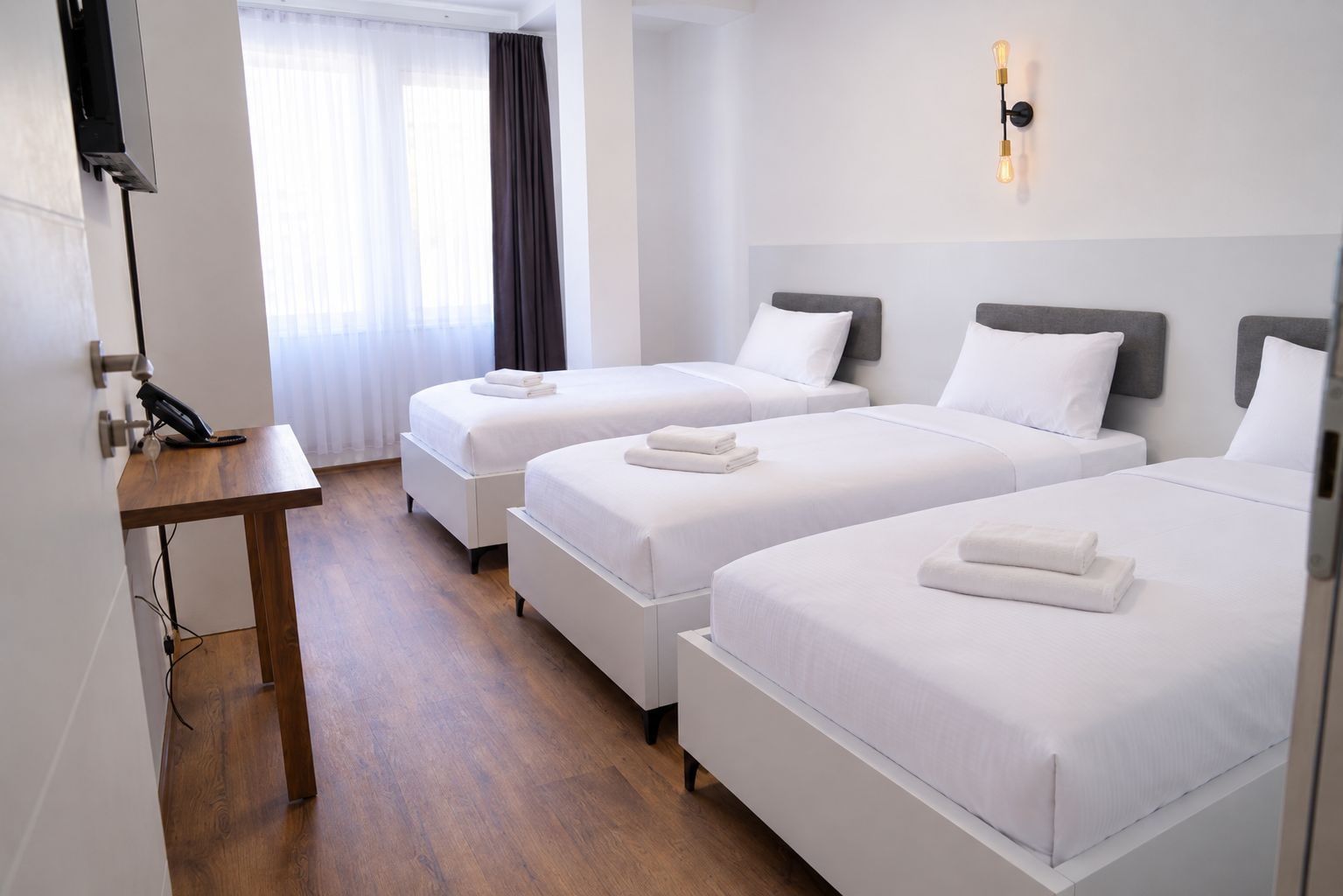 Habitación de hotel con dos camas, un escritorio y un teléfono.