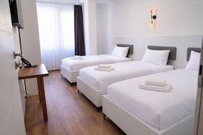 Habitación de hotel con dos camas, un escritorio y un teléfono.