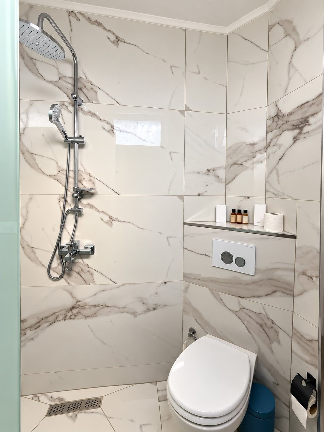 A bathroom with a shower, toilet, and a soap dispenser on the wall.