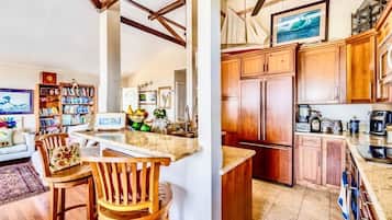 A kitchen with wooden cabinets, a built-in island, and a dining area with a wooden chair and table.