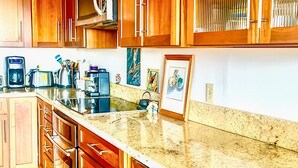 A kitchen with wooden cabinets, a granite countertop, and a stainless steel range hood. - Hale Akala - Huahine (Shared Bathroom) (Kailua-Kona)