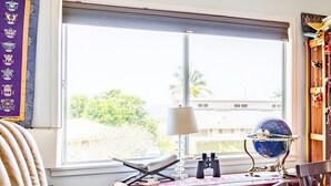 Ein Zimmer mit Schreibtisch, Stuhl, Globus und einem Fenster mit Blick auf Grünflächen.
