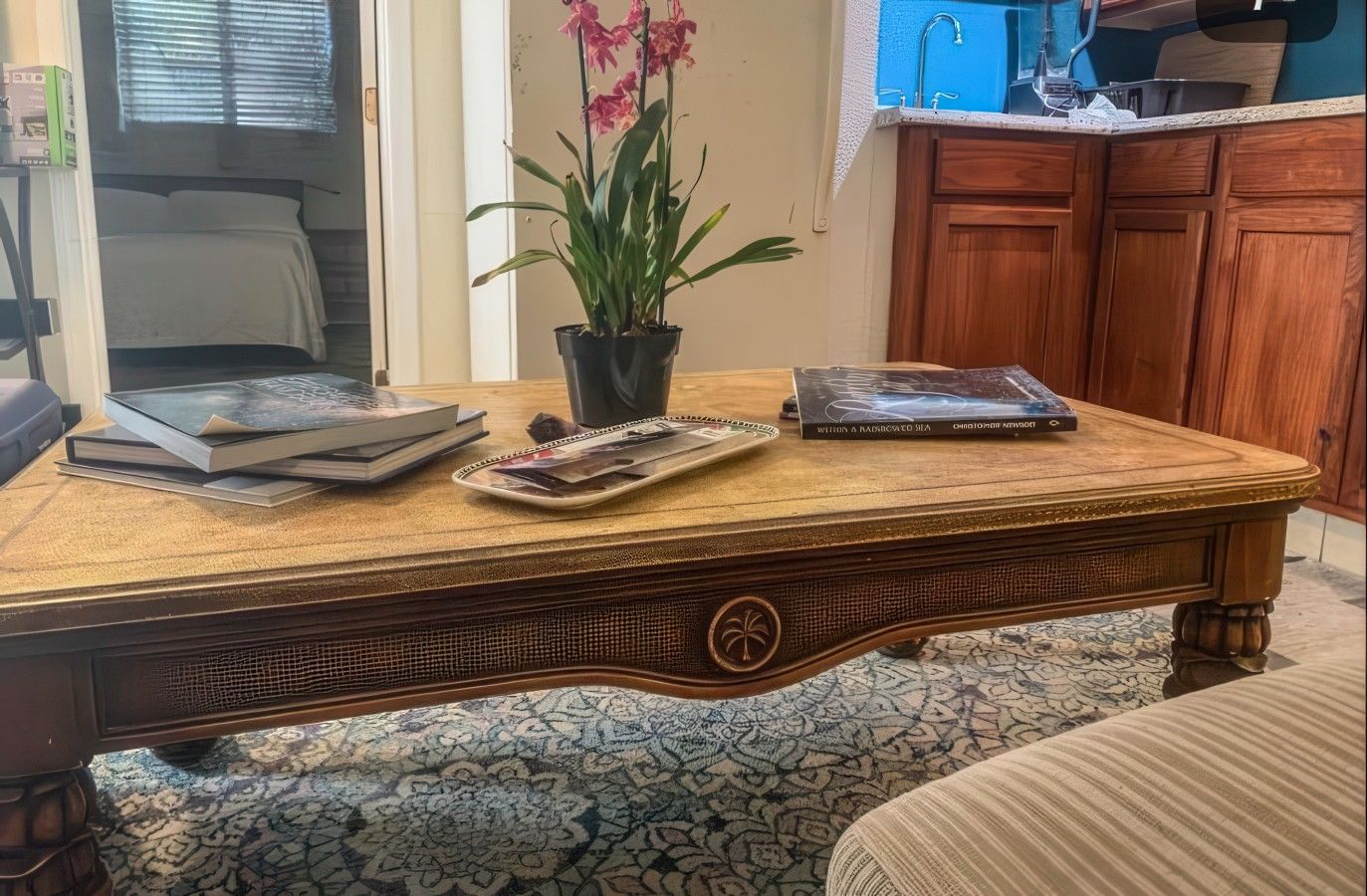 A wooden table with a tray of magazines, a book, and a potted plant.