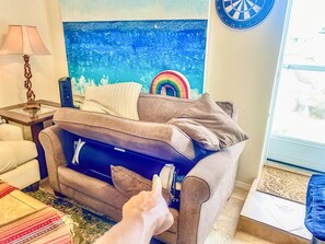 Quarto com sofá, luminária, alvo de dardos e janela com vista.