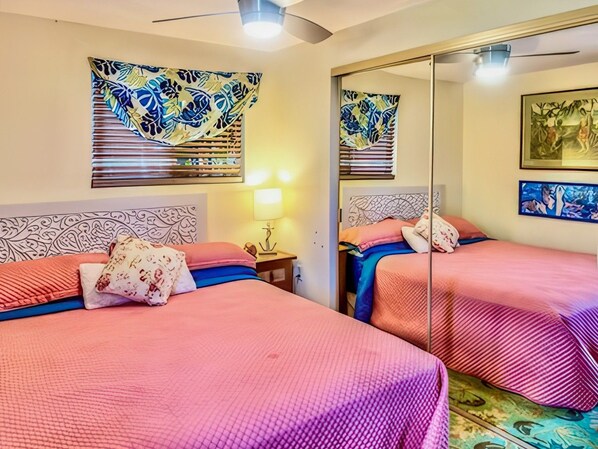 Habitación de hotel con dos camas, una mesita de noche, una lámpara y obras de arte en las paredes.