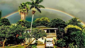 A two-story house with a balcony, surrounded by lush greenery and a visible rainbow. - Hale Akala - Hanalei (Shared Bathroom) (Kailua-Kona)