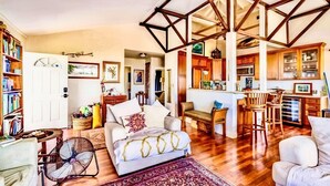 A spacious living room with a large sofa, a dining area with wooden chairs, and a kitchen with wooden cabinets. - Hale Akala - Hanalei (Shared Bathroom) (Kailua-Kona)