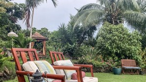 A garden with two wooden chairs, a lantern, and a gazebo. - Hale Akala - Hanalei (Shared Bathroom) (Kailua-Kona)