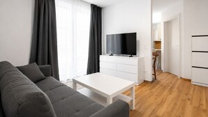 A modern living room with a grey sofa, a white coffee table, and a flat-screen TV on a white cabinet. - Haus3310 - Top 2, Balcony & Central (Bad Hofgastein)