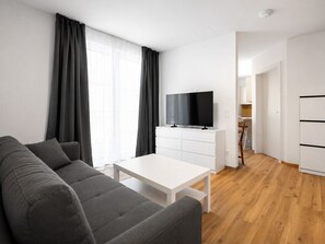 Ein modernes Wohnzimmer mit einem grauen Sofa, einem weißen Couchtisch und einem Flachbildfernseher auf einem weißen Schrank.