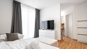 A modern hotel room with a bed, a flat-screen TV, a white dresser, and a wooden floor. - Haus3310 - Top 2, Balcony & Central (Bad Hofgastein)