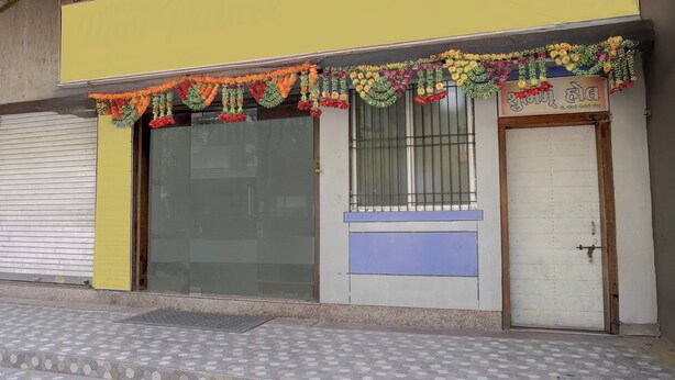 A storefront with a closed shutter, a metal gate, and a tiled entrance. - MG Road Crossway Formerly Ravi Palace (Rajkot)