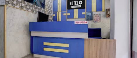 A hotel reception area with a reception desk, a sign indicating 'HOTEL COMPANY Serviced', and a 'RECEPTION' sign.