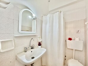 A bathroom with a white sink, mirror, and toilet.