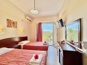A hotel room with two beds, a TV, a balcony with a view, and a painting on the wall.