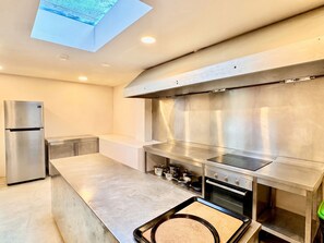 A modern kitchen with a stainless steel refrigerator, oven, and a large island with a built-in stovetop.