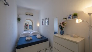 Une chambre d’hôtel comprenant un lit, une table de chevet, un miroir, un climatiseur fixé au mur et une fenêtre donnant sur la mer.