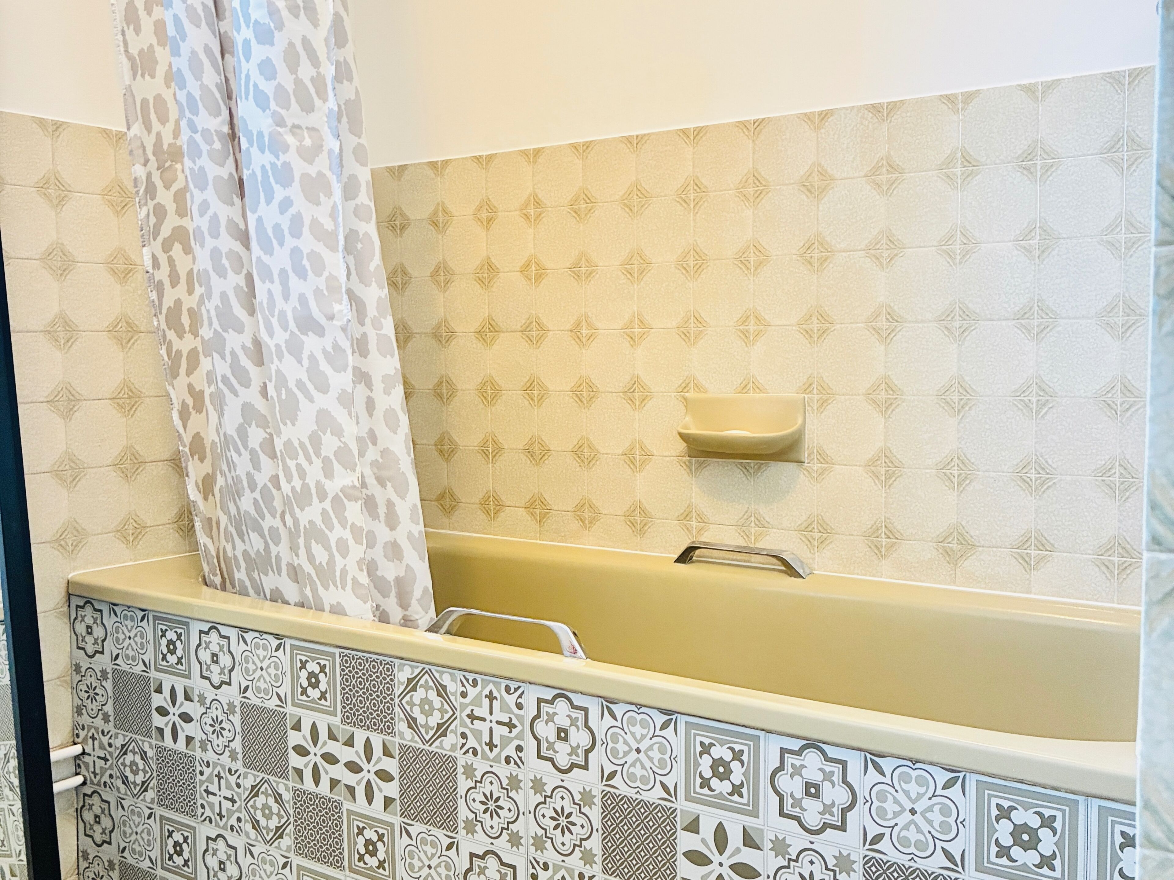 A bathroom with a bathtub, patterned tiles, and a shower curtain.