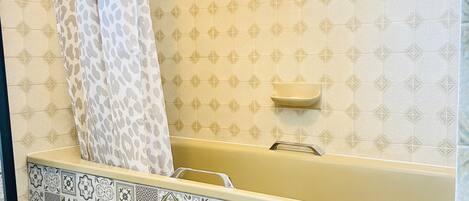 A bathroom with a bathtub, patterned tiles, and a shower curtain.