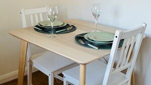 A dining table with two chairs, a wine glass, and a plate set. - Grays Cosy 1-Bed Apartment Sleeps 4 near Station (Grays)