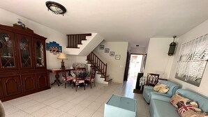 Un salon avec un escalier, un coin repas et un canapé agrémenté de coussins décoratifs.