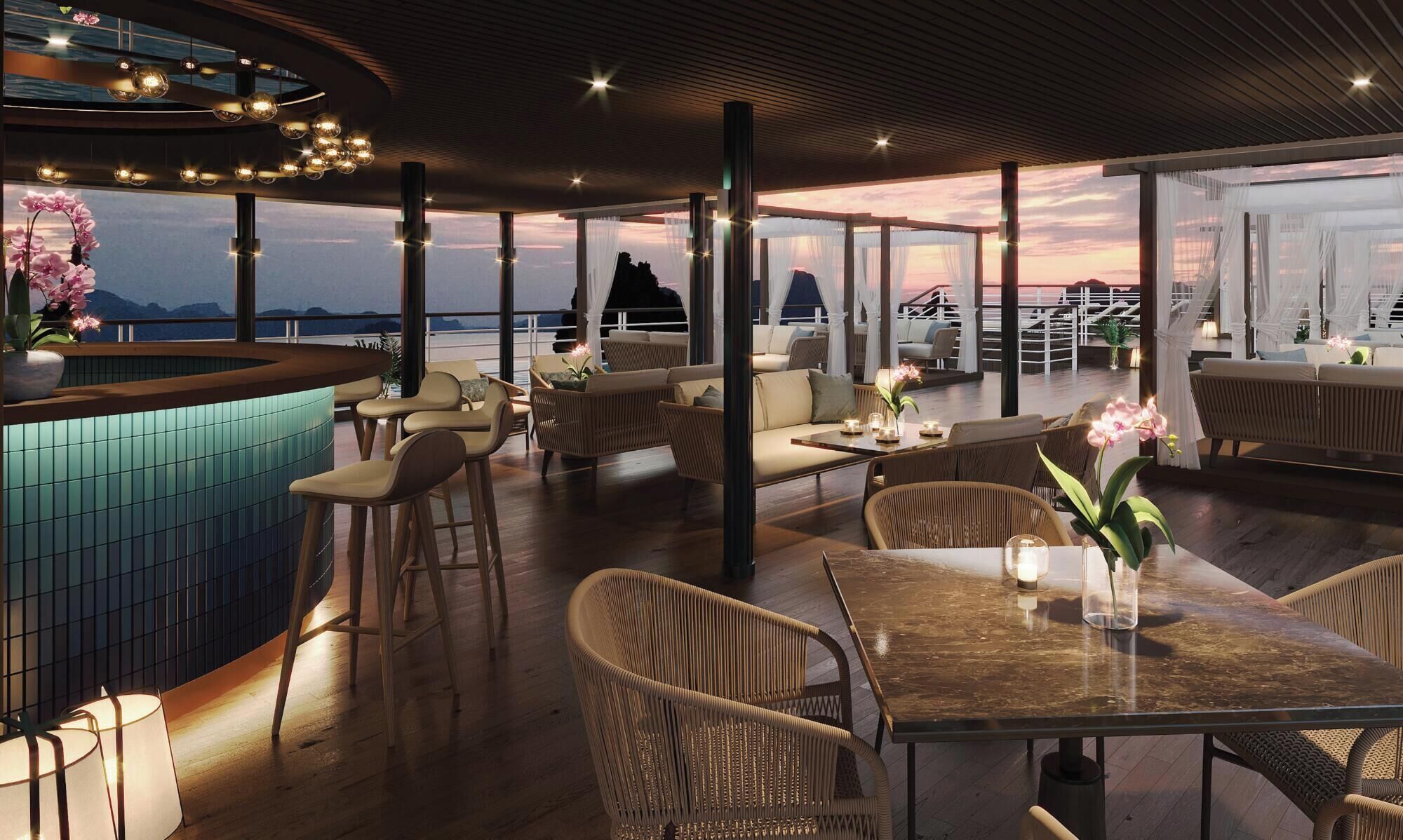 A spacious outdoor seating area with a view of the ocean and mountains, featuring wicker furniture and a bar area.
