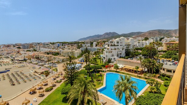 Een resort met een zwembad, een strandgedeelte en uitzicht op de bergen.