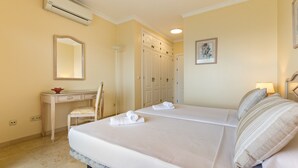 Een hotelkamer met een bed, een bureau, een stoel, een kledingkast en een airconditioning.