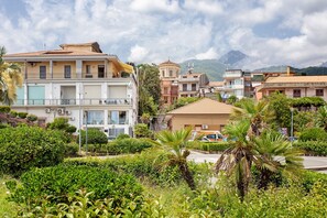 A residential area with multi-story buildings, some with balconies, and a mountainous backdrop. - 'Haddar Etna' - Amber (Zafferana Etnea)