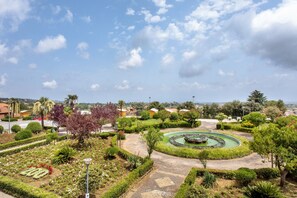A landscaped garden with a circular water feature, pathways, and various plants. - 'Haddar Etna' - Amber (Zafferana Etnea)