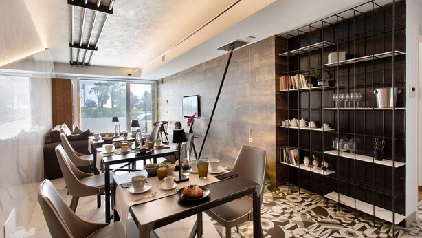 Een moderne eethoek met een lange tafel, stoelen en een boekenkast vol diverse spullen.