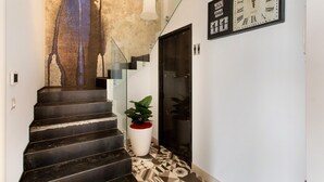 A staircase with a textured wall, a potted plant, and a wall clock. - 'Haddar Etna' – Sapphire (Zafferana Etnea)