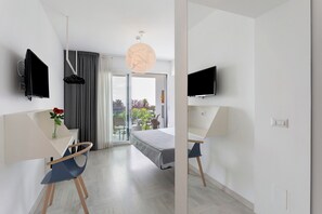 Une chambre d’hôtel moderne équipée d’un lit, d’un bureau, d’une chaise, d’une télévision et offrant une vue sur l’extérieur.