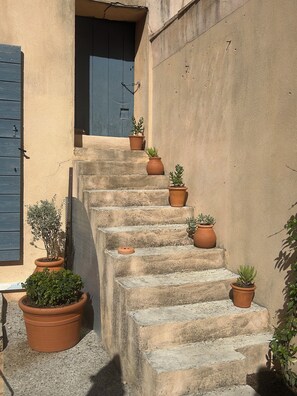 A set of stone steps leading to a door with a blue shutter, surrounded by potted plants. - Lodge in the heart of a vineyard in Provence – Cassis and the sea are less than 10 minutes away (Roquefort-la-Bédoule)