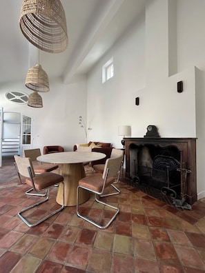 A dining area with a round table and chairs, a fireplace, and a view of a staircase. - Lodge in the heart of a vineyard in Provence – Cassis and the sea are less than 10 minutes away (Roquefort-la-Bédoule)