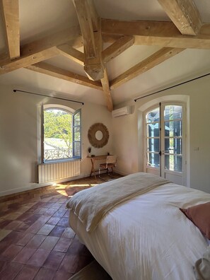 Quarto com cama, escrivaninha, cadeira, janela e porta.