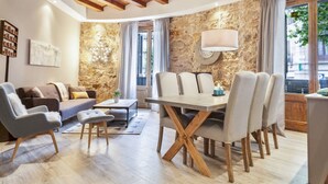 Ein modernes Wohnzimmer mit Steinwand, einem Esstisch mit Stühlen, einer Couch und einem Couchtisch.
